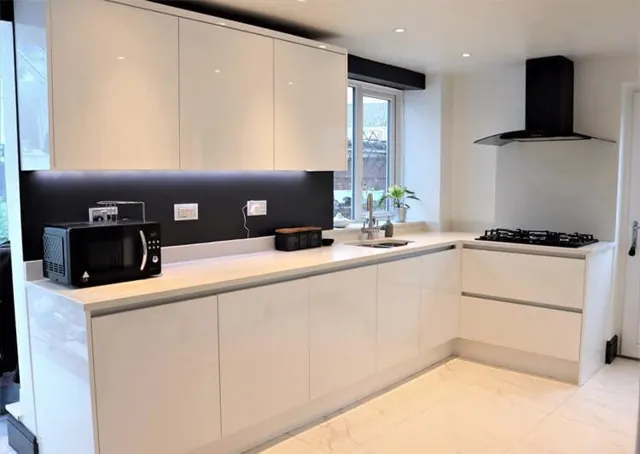 Contemporary cream handleless kitchen with dark splashback and chimney extractor