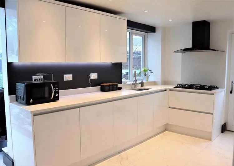 Contemporary cream handleless kitchen with dark splashback and chimney extractor