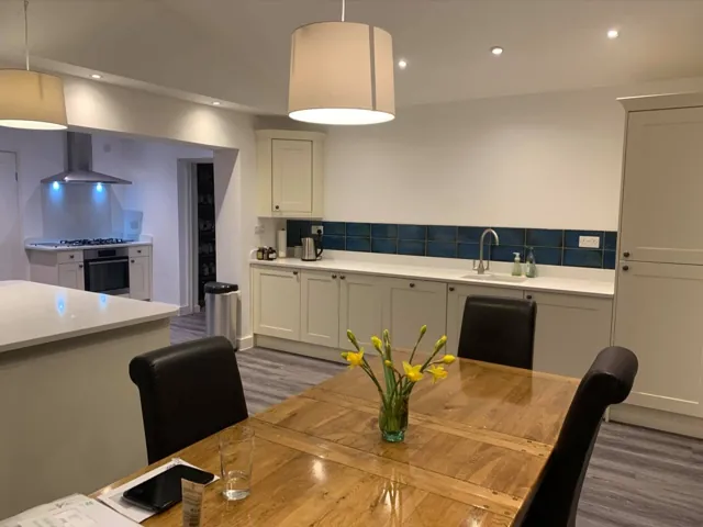 Cream Shaker kitchen with teal tiled splashback and open-plan dining table