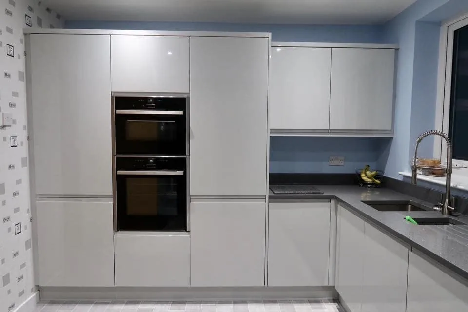 Light grey handleless kitchen with tall tower units and built-in double oven