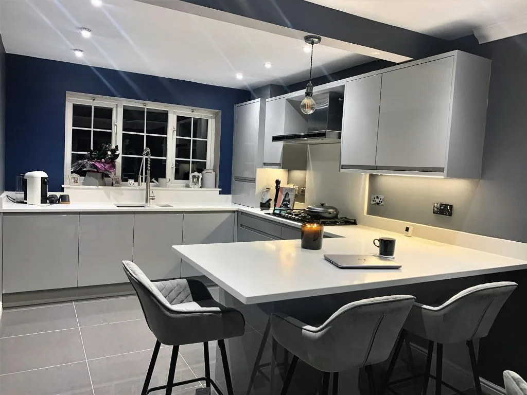 Light grey kitchen with peninsula breakfast bar, bar stools and navy walls