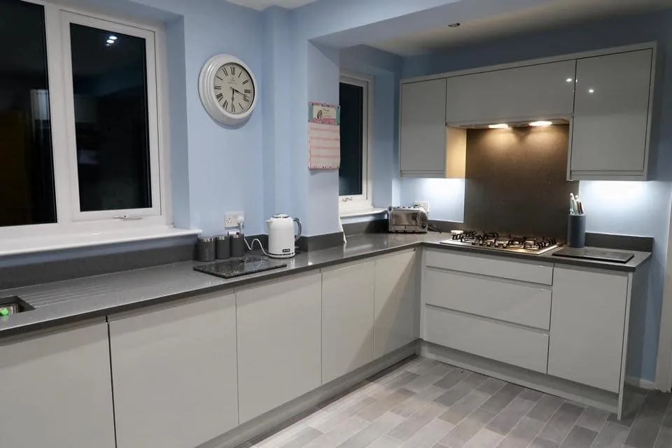 Light grey kitchen with dark worktops in an L-shaped layout