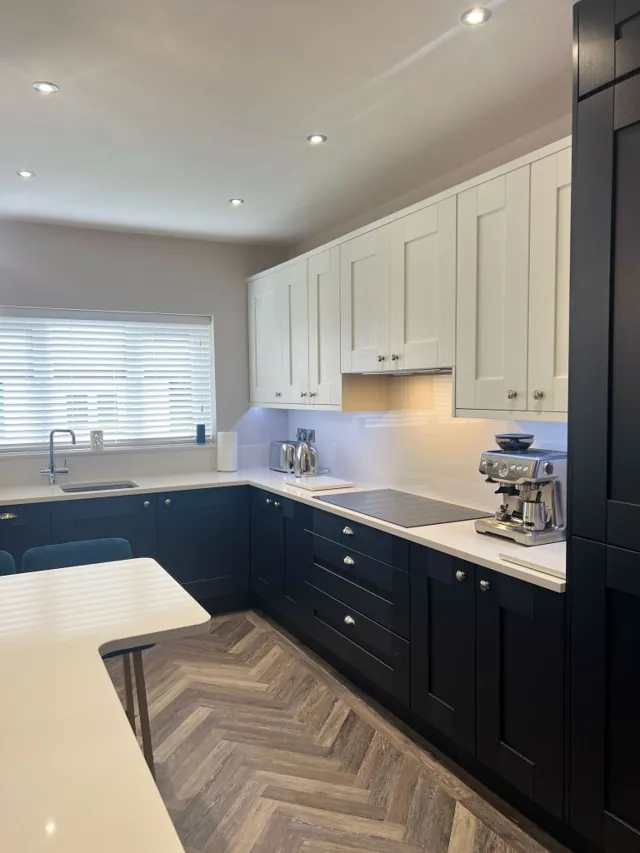 Two-tone navy and cream Shaker kitchen with breakfast bar and herringbone floor