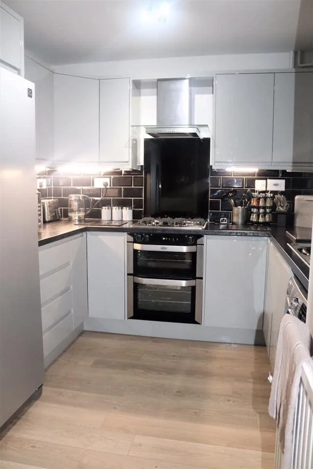 White gloss kitchen with range cooker and brick-effect splashback